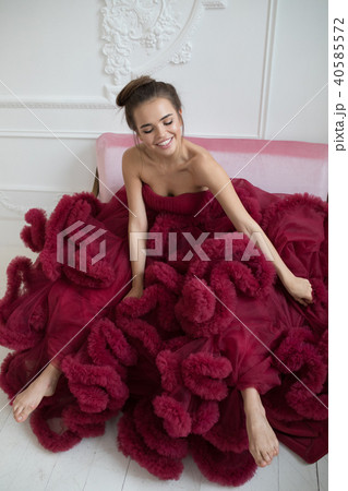 Cheerful young woman in a burgundy ball gown. 40585572