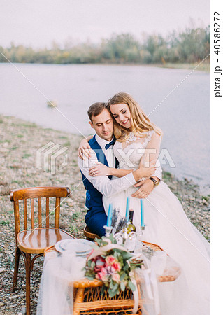 Sensitive outdoor portrait of the bride sitting on the groom on the coast. 40586272