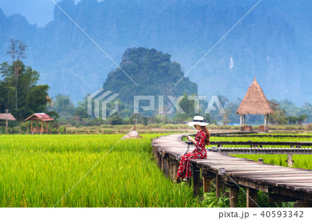 Young woman sitting on wooden path with green rice 40593342