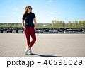 Stylishly dressed young woman in glasses stands in the middle of a stone square against the 40596029