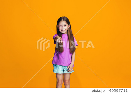 The happy teen girl pointing to you, half length closeup portrait on orange background. 40597711