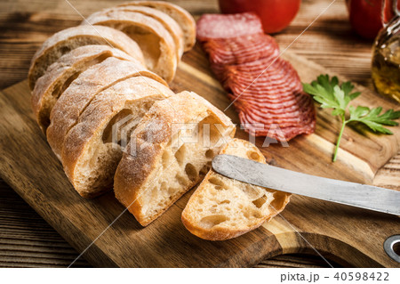 Italian ciabatta bread cut in slices with salami. 40598422