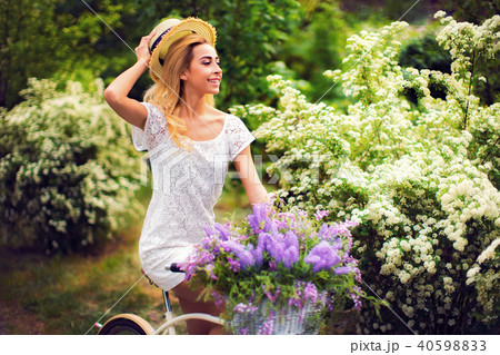 beautiful young girl with vintage bicycle and flowers on city background in the sunlight outdoor. 40598833