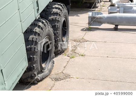 Flat tire of old military heavy truck. General-purpose air bombs on background. Army decay and Flat tire of old military heavy truck. General-purpose air bombs on background. Army decay and 40599000