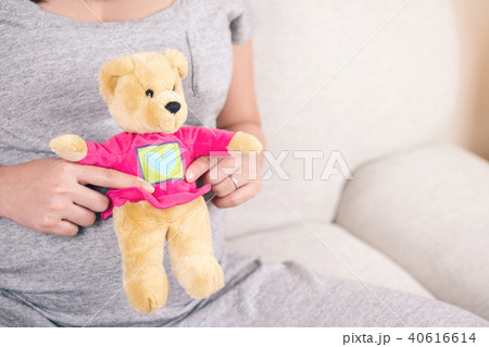 Pregnant woman hand holding teddy bear doll. 40616614