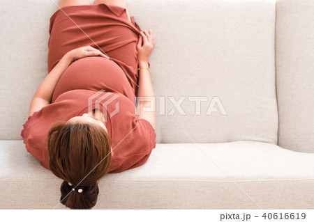 Young pregnant woman sitting on gray sofa top view 40616619