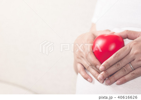 Happy pregnant woman holding love red heart shape. 40616626