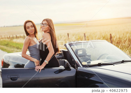 Girls posing for the camera in a black convertible Girls posing for the camera in a black convertible 40622975