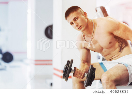 Beautiful athletic bodybuilder guy, carries out exercises with d 40628355