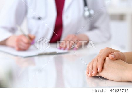 Female doctor filling up  an application form while consulting patient. Just hands. Medicine an 40628712