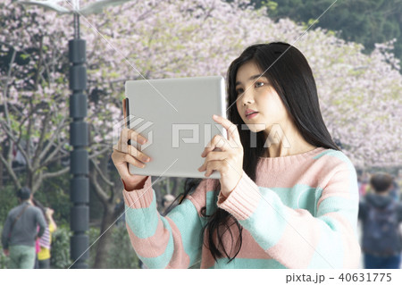 Girl taking photo of blooming flower with tablet. 40631775