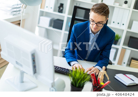A young man is working at the computer in the office. A young man is working at the computer in the office. 40648424