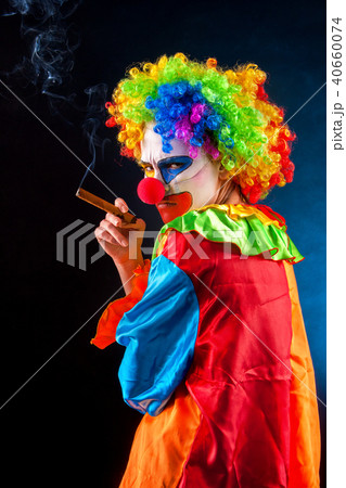 Mad clown on black background. Woman is smoking cigar. 40660074
