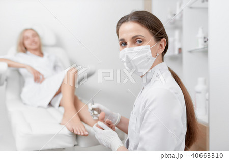 Podiatrist in mask on face looking at camera and working. 40663310
