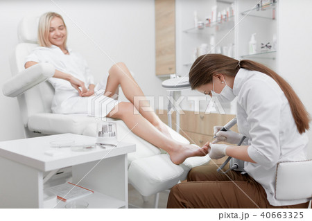Podiatrist making procedure for smiling clients foot. 40663325