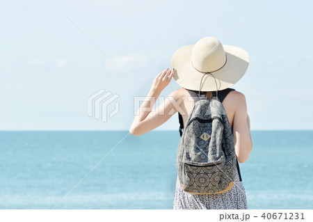 Girl in a hat standing on the coastline. Back view 40671231