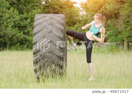 Girl in sports clothes is hitting the tire 40671417