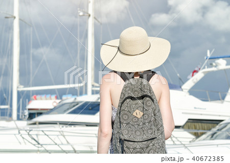 Girl in a hat with a backpack near ship. Back view Girl in a hat with a backpack near ship. Back view 40672385