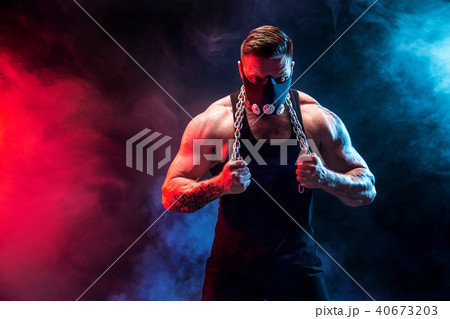 Strong male athlete in a black training mask on a black background 40673203