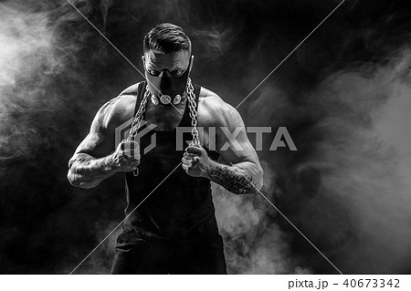 Portrait of muscular sportsman with metal chain. Black background with smoke Portrait of muscular sportsman with metal chain. Black background with smoke 40673342