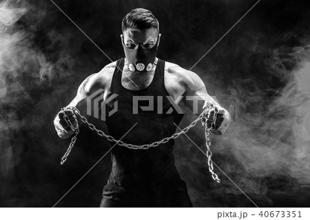Portrait of muscular sportsman tearing metal chain. Black background with smoke Portrait of muscular sportsman tearing metal chain. Black background with smoke 40673351