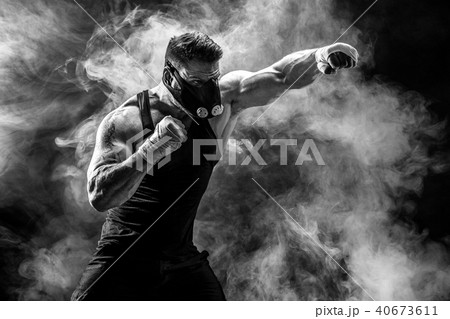 Strong male athlete in a black training mask on a black background 40673611