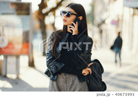 stylish girl walking through the city while using her phone 40673993
