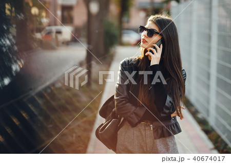 stylish girl walking through the city while using her phone 40674017