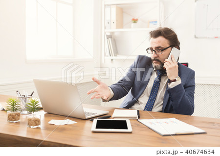Serious businessman talking on mobile phone Serious businessman talking on mobile phone 40674634