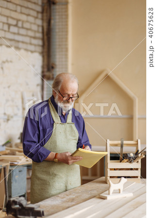 old shop teaher is sketching with pencil and notepad near the table old shop teaher is sketching with pencil and notepad near the table 40675628