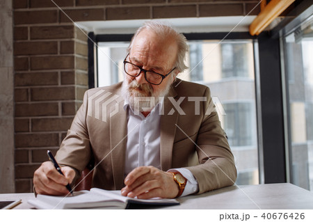 atractive experienced old man writing important information in the notepad atractive experienced old man writing important information in the notepad 40676426
