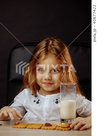 Happy beautiful little girl having a snack with milk and cookies 40677422