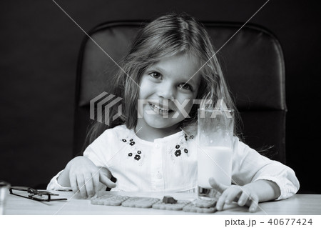 Happy beautiful little girl having a snack with milk and cookies 40677424