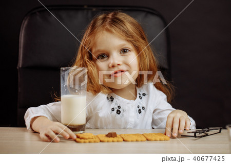 Happy beautiful little girl having a snack with milk and cookies 40677425