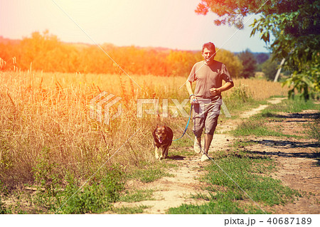 A man with a dog walks along a rural road 40687189