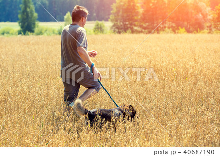 Man with dog running in an oat field in summer 40687190