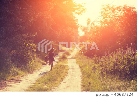 A little girl with a dog runs along a country road 40687224