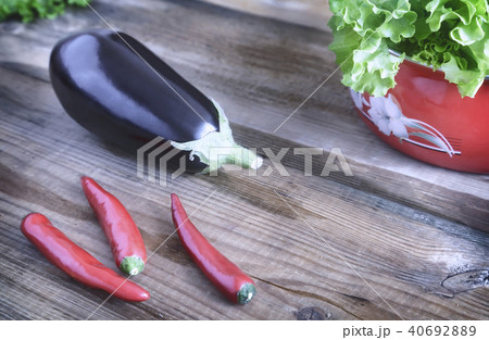 Green salad, eggplant and chili on a wooden table. 40692889