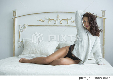 Beautiful young girl with curly hair lies in bed in the morning in a sexy suit and smiles. Morning 40693687
