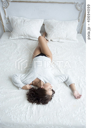 Top view Beautiful young sexy girl with slender legs lying on the bed, morning boudoir shooting girl Top view Beautiful young sexy girl with slender legs lying on the bed, morning boudoir shooting girl 40694099