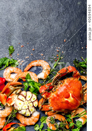 Fresh raw seafood - shrimps and crabs with herbs and spices on dark gray background. Copy space Fresh raw seafood - shrimps and crabs with herbs and spices on dark gray background. Copy space 40694894