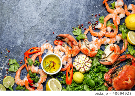 Fresh raw seafood - shrimps and crabs with herbs and spices on dark gray background. Copy space 40694923