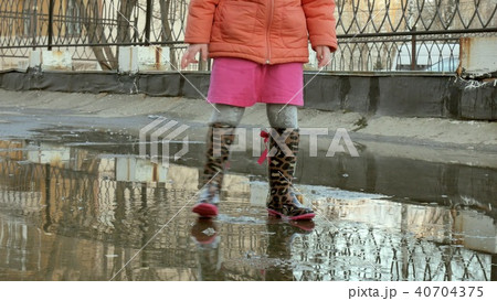 Little beautiful girl jumping on puddles after rain Little beautiful girl jumping on puddles after rain 40704375