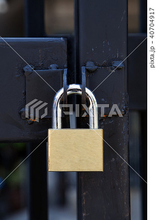 Closeup brass padlock on a black metal gate. 40704917