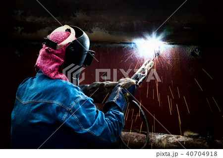 Steel welder with mask welding metal and sparks. 40704918