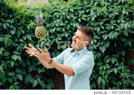 cheerful emotional guy holding a pineapple. cheerful emotional guy holding a pineapple. 40716558