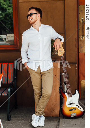 cheerful handsome guy stands near a guitar cheerful handsome guy stands near a guitar 40718217