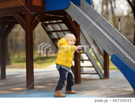 Little boy having fun on outdoor playground on spring or fall day 40720035