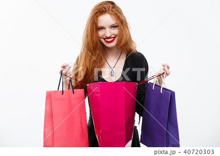 Halloween witch concept - Happy Halloween Witch smiling and holding colorful shopping bags on white 40720303