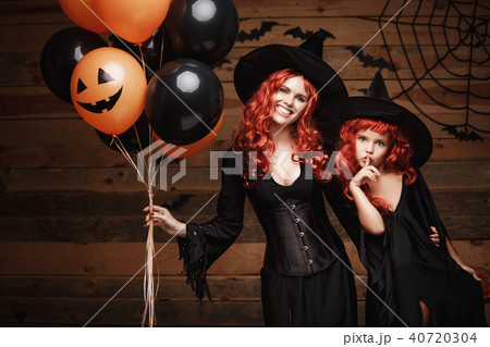 Halloween Witch Concept - cheerful mother and her daughter in witch costumes celebrating Halloween 40720304